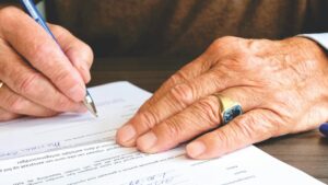 older man signing a document for asset protection