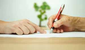 hand of an elderly man holding a pen and sighing a document